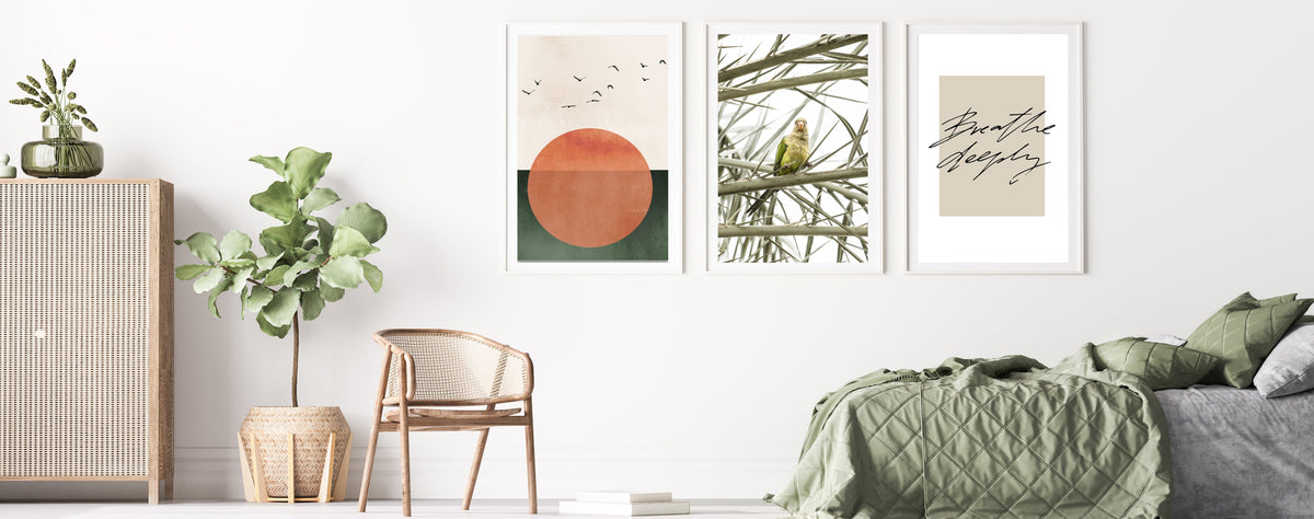 Selection of three modern art prints in greens and reds in a bedroom setting